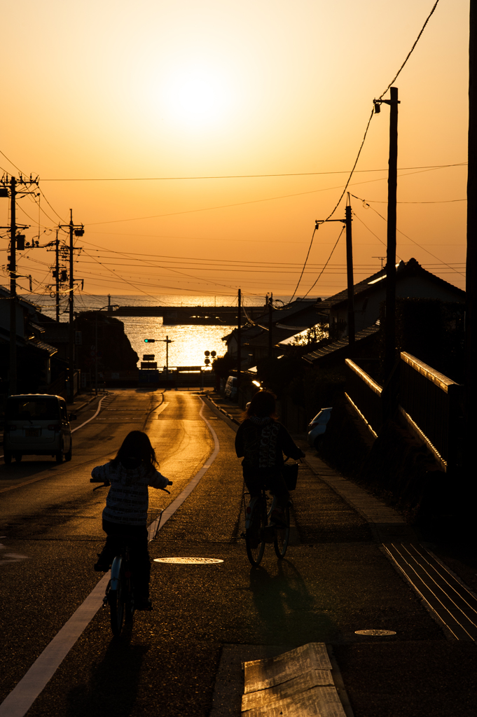 稲佐の浜への下り坂、自転車で向う親子。