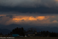 Clouds dyed orange between 
the rain clo