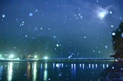 月夜の嵐山に雪が舞う