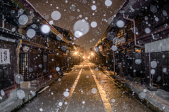金色に染まる三町に雪が舞う