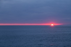 水平線と雲の間に沈む夕日