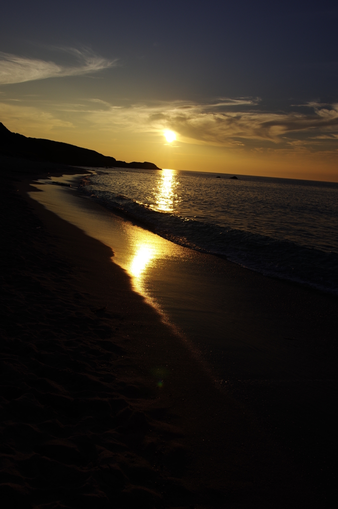 沈む夕日に波音が響く