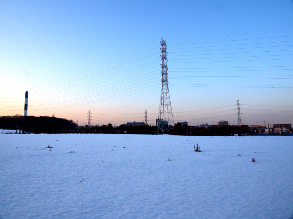 白くなった畑と青白になった煙突と送電塔