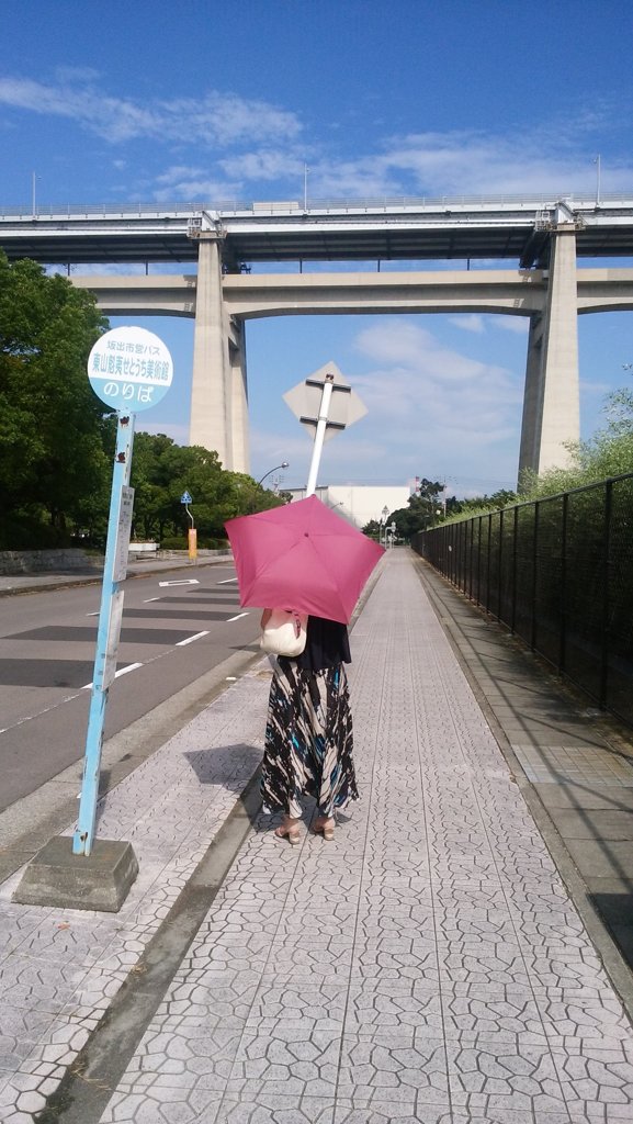 バス停の赤い傘の女