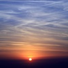 海に映る夕日と飛行機雲 