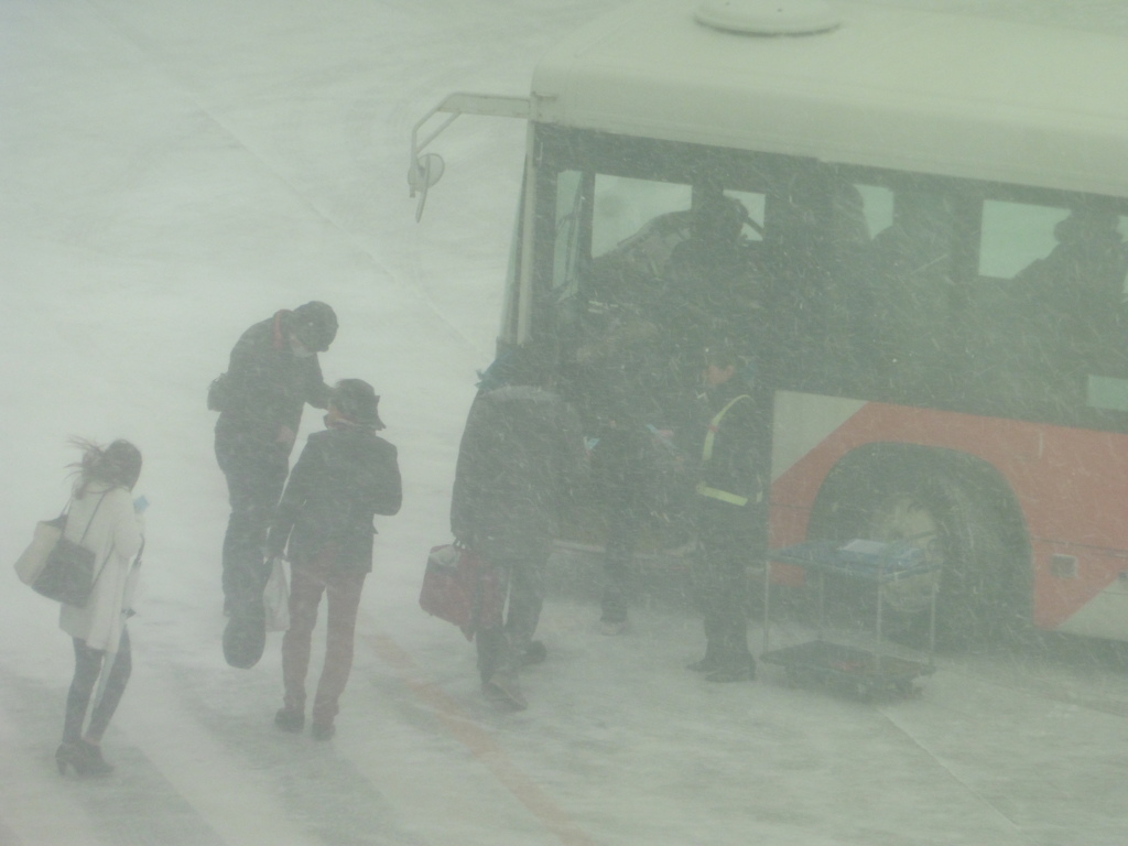 吹雪の中バスに乗り込む乗客