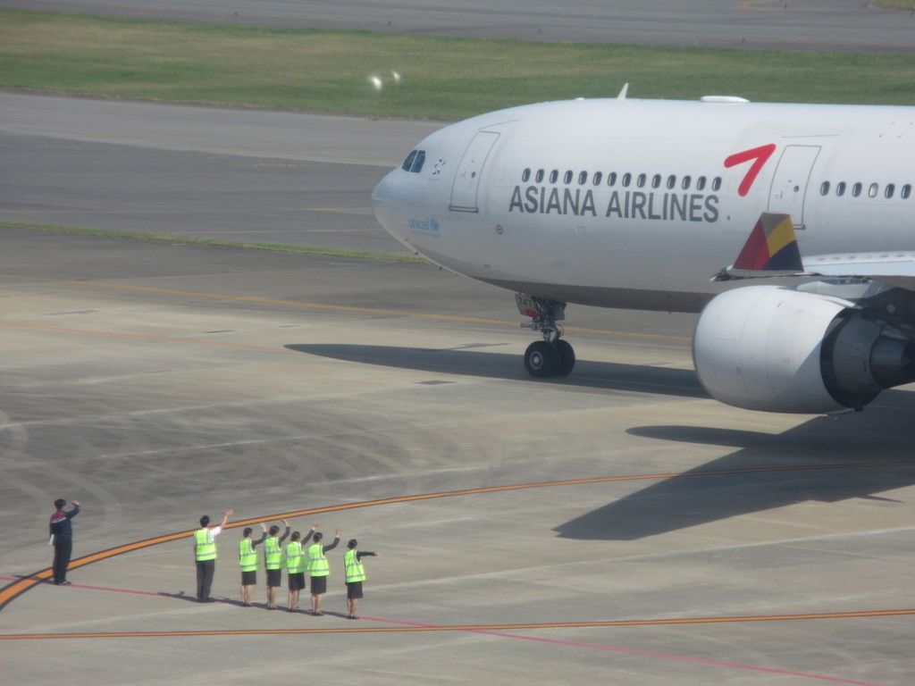 出発するアシアナと手を振って見送る社員