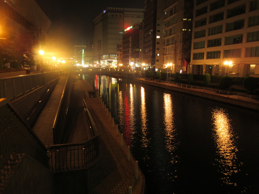 夜の繁華街を流れる川と外灯の光