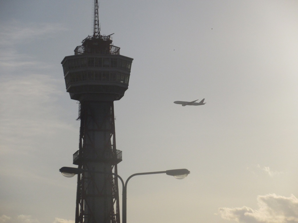 博多ポートタワーと上空を通過する飛行機