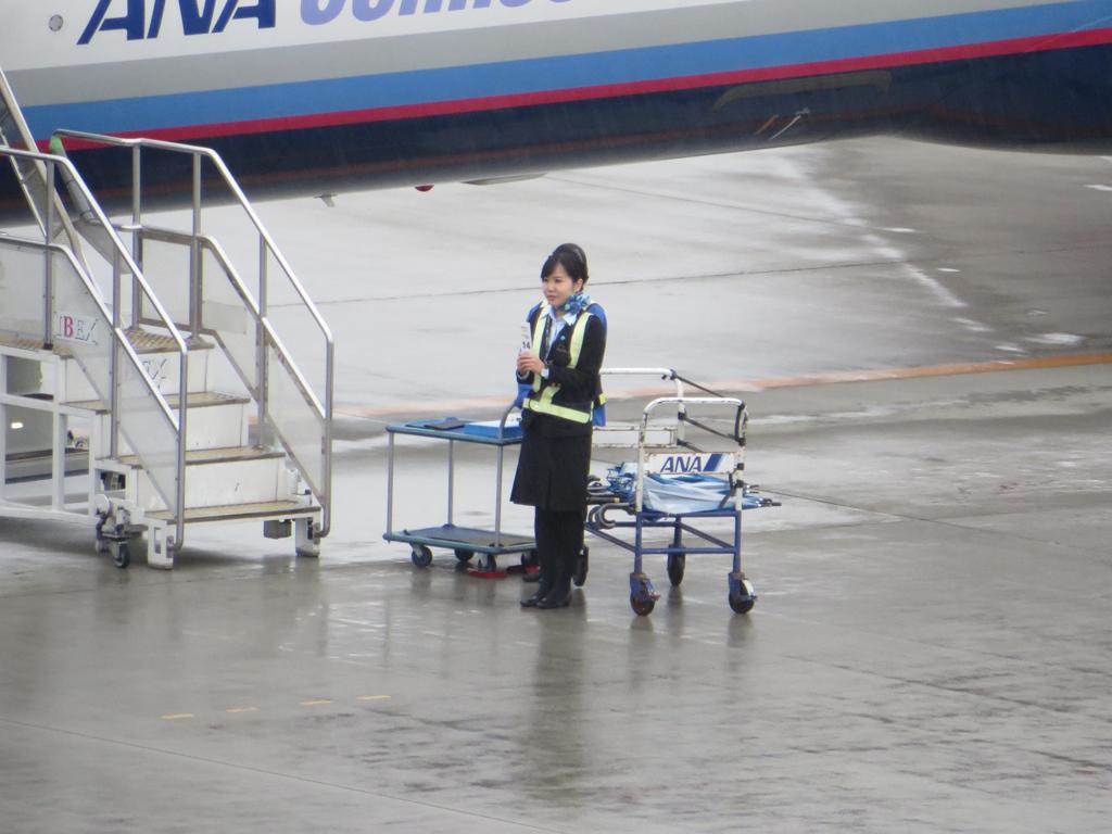 雨の中搭乗案内をするANA社員の女性