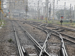 雨の日の濡れたレールと奥に見える車両基地