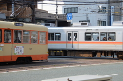 踏切前で電車が電車の通過を待つ
