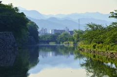 青い山並みを眺めるお濠の風景