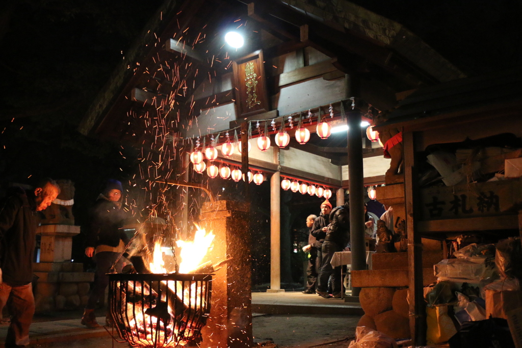 炎で暗闇から白く浮かび上がる社