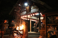 炎で暗闇から白く浮かび上がる社