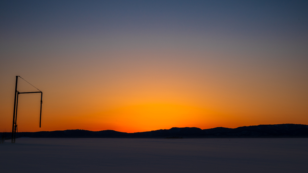 雪積もる畑、夕陽に照らされ。