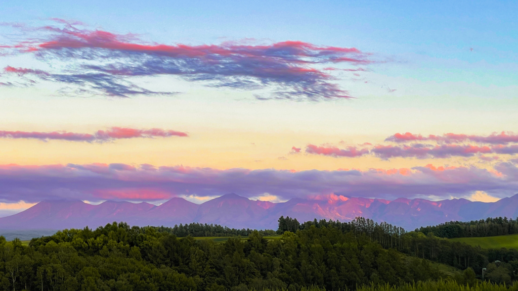 夕陽の反射でピンクに染まる十勝岳の山々。