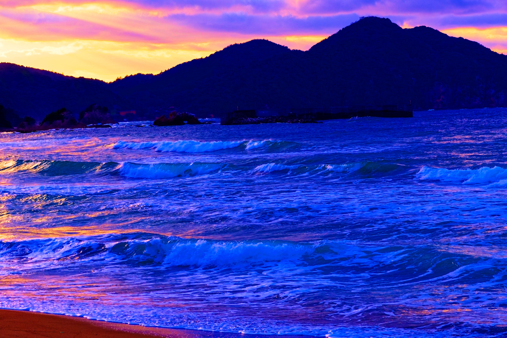 紅く染まる夕暮れの海岸と荒波