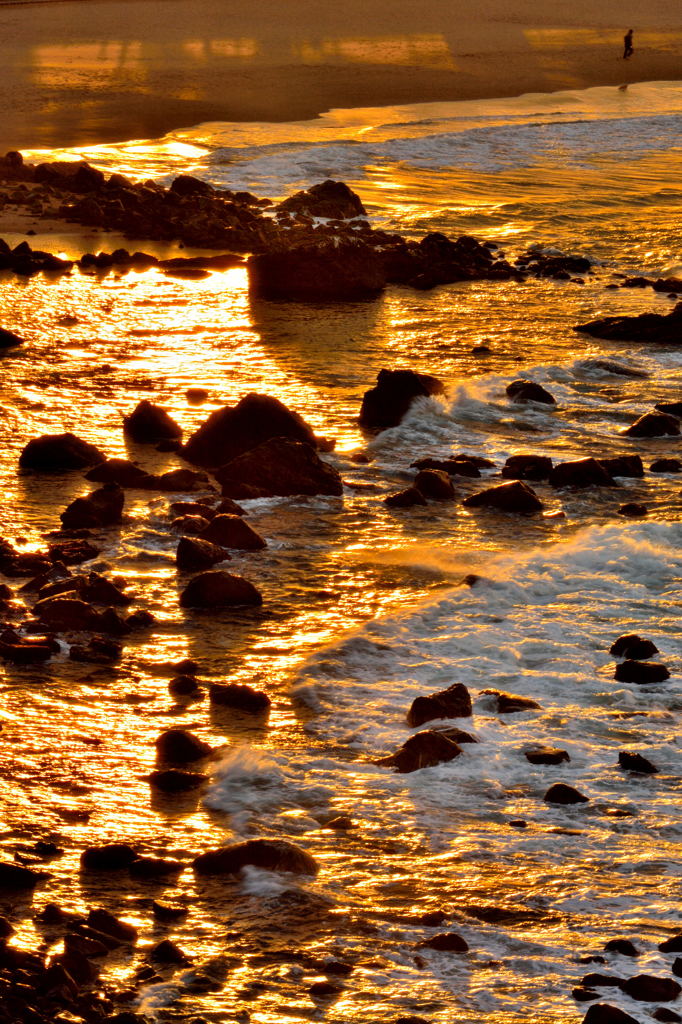 夕日に染まる岩場と波