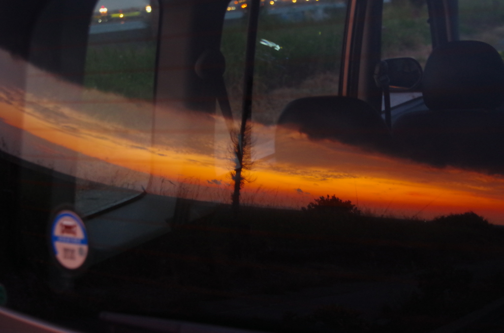 一雨来そうな夕焼け空　車のリアガラスに映りこみ