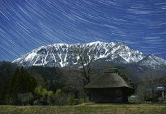 早春の大山と茅葺小屋