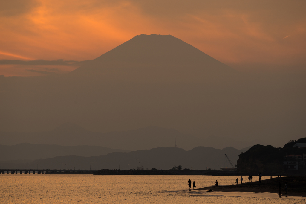 富士山のシルエットを砂浜より望む人々