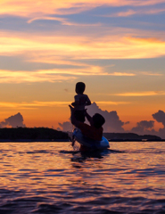 夕暮れの海で遊ぶ親子