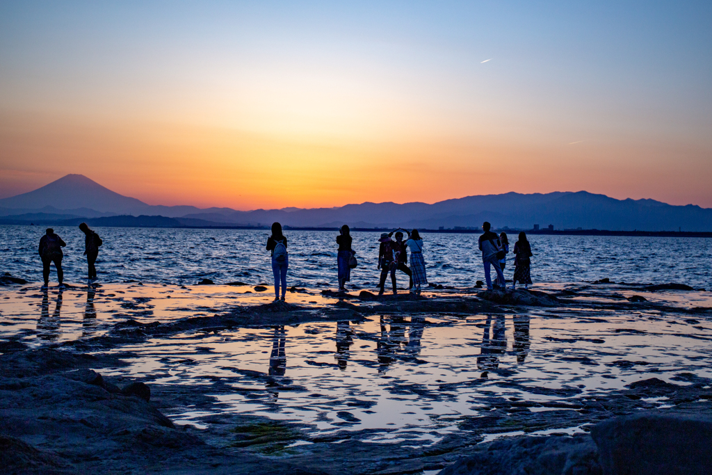 名残惜しい夕日の光と水面に映る人々のシルエット。