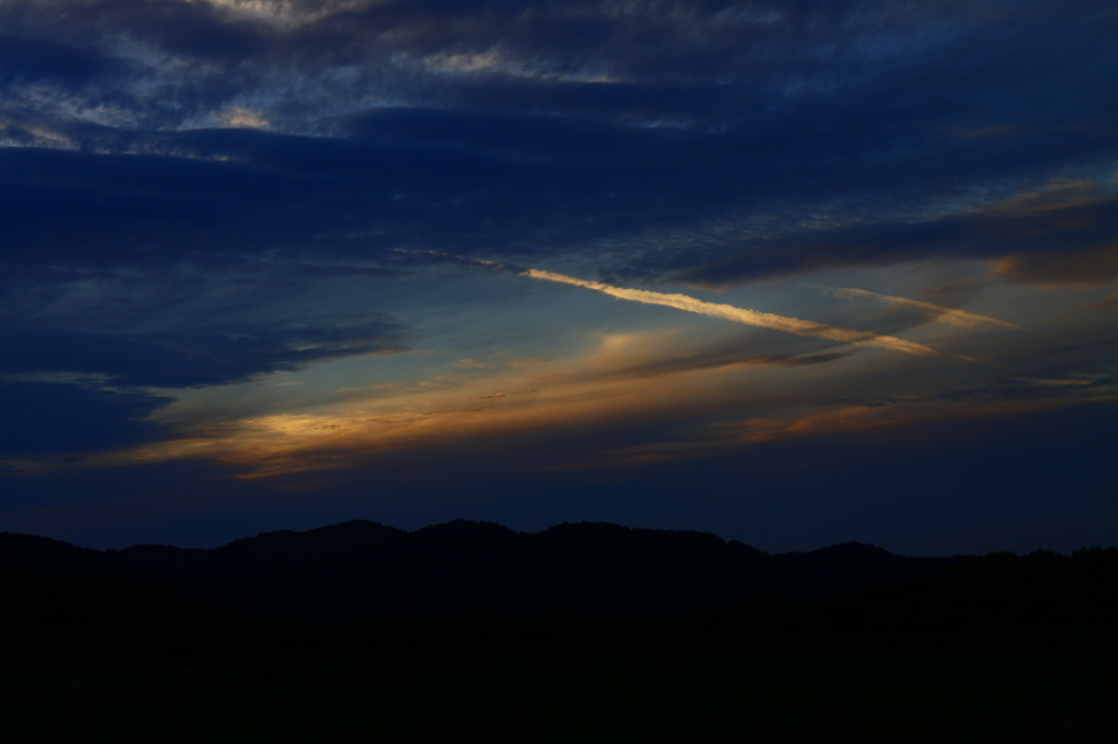 飛行機雲織り成す夕陽