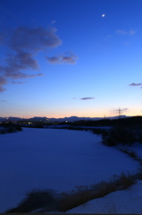 夕暮れの川に積もる雪