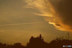 大きな雲に突き刺さる飛行機雲