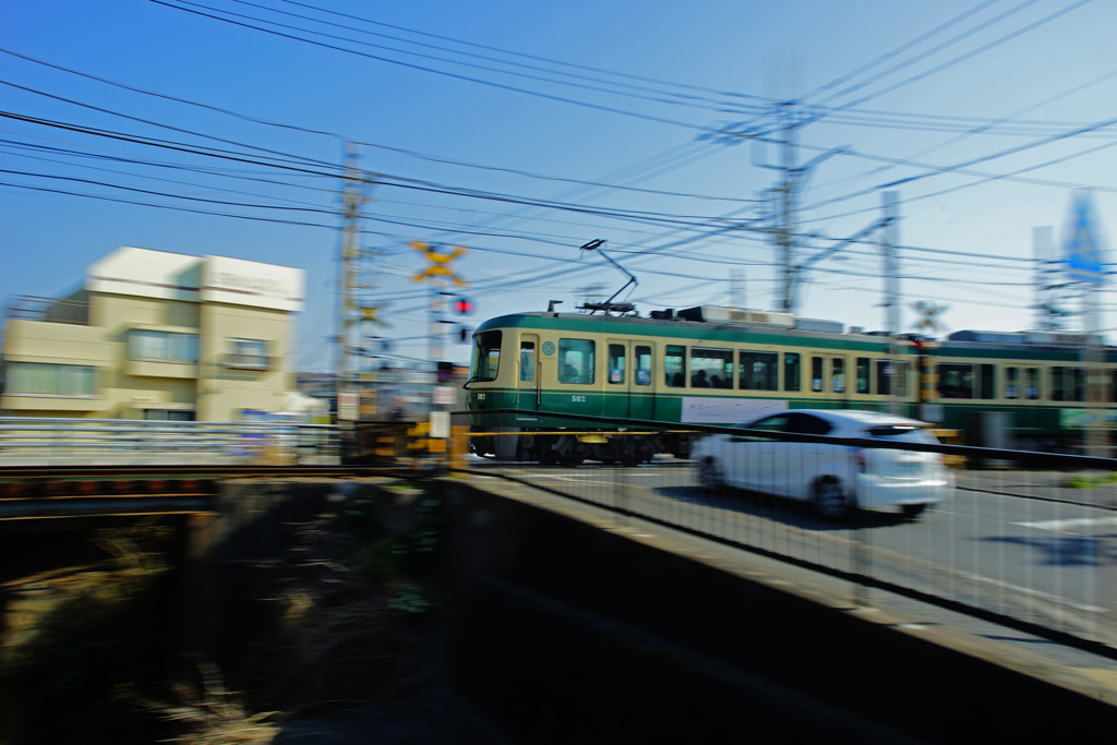 春の朝、ゆっくりと踏切を通過する江ノ電