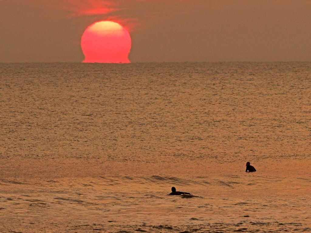 日の出とサーファー