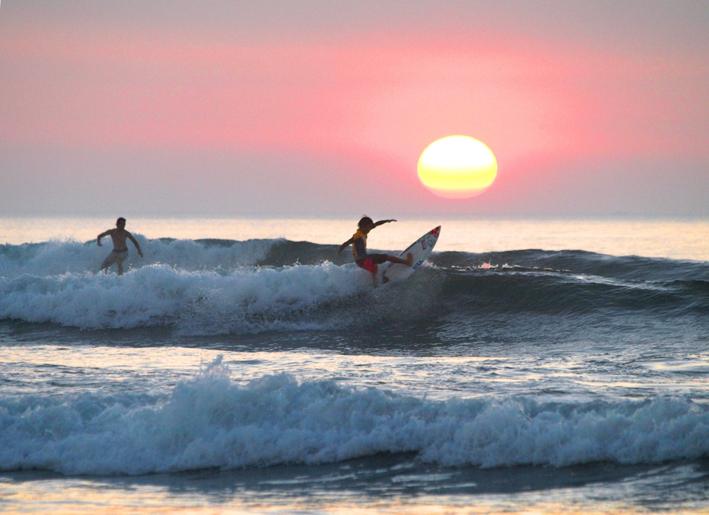 日の出と少年サーファー