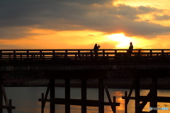朝陽を浴びる渡月橋で写真を撮る人