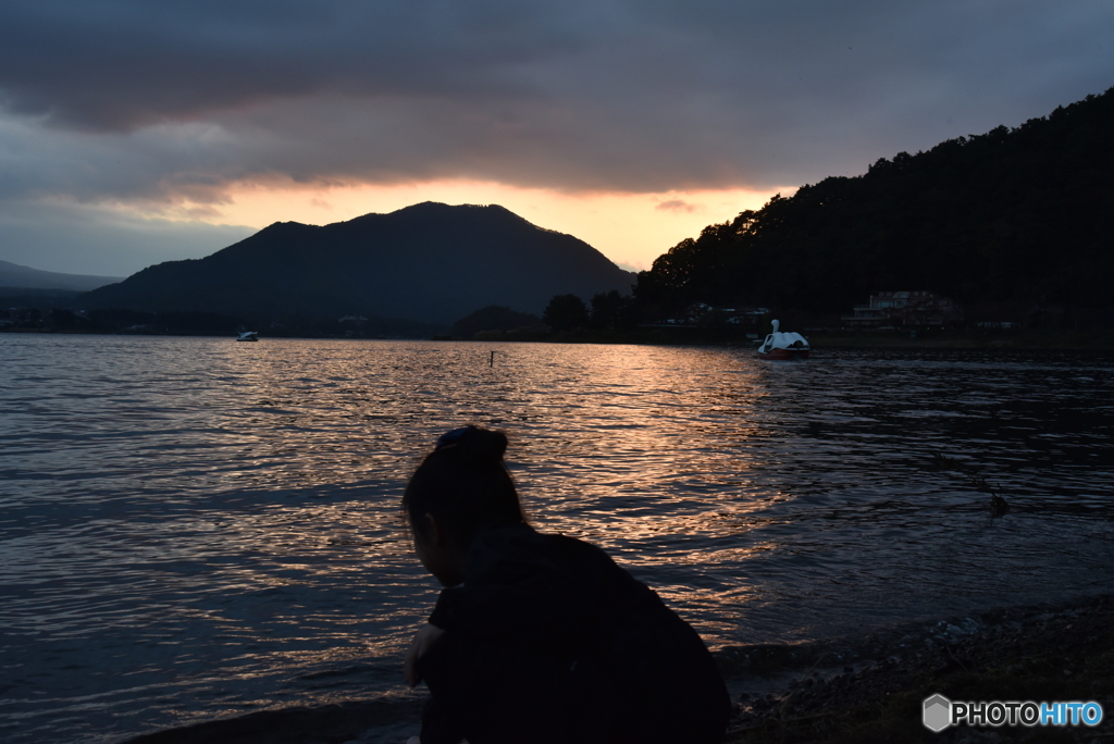 夕暮れの湖畔を撮る娘