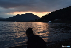 夕暮れの湖畔を撮る娘