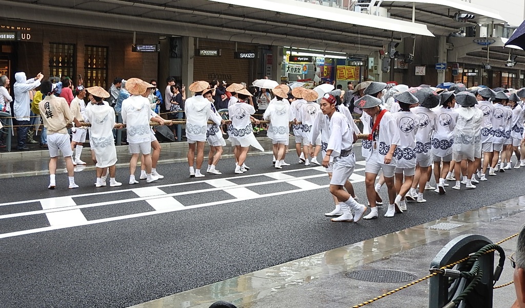 雨の中にて大勢での鉾の引き手