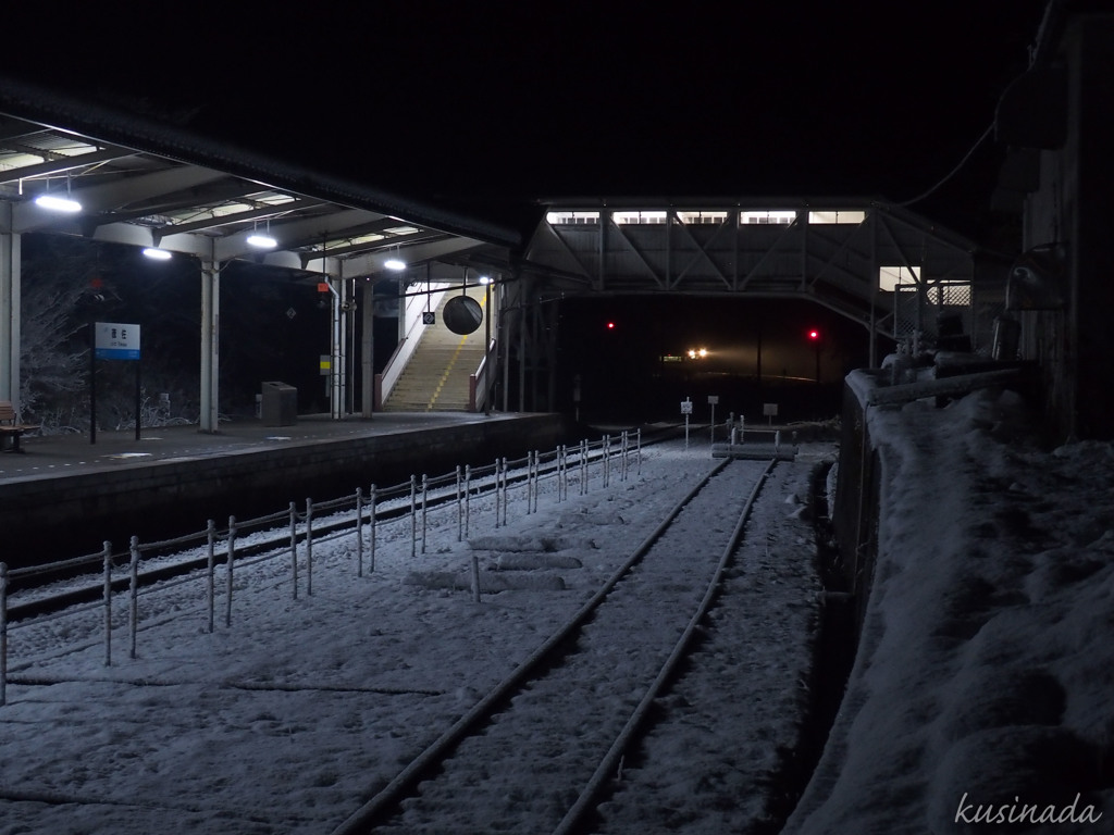 雪の駅に近づく灯り