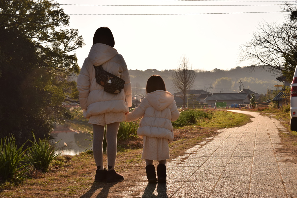 夕暮れ時、川沿いの姉妹。