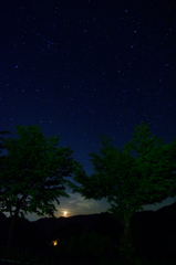 西に沈む月と星空