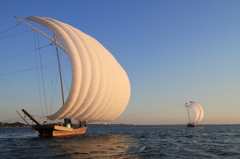 夕陽を受けて進む帆引き船