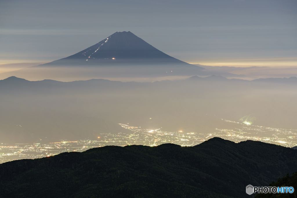 霞む街明かりと登山者