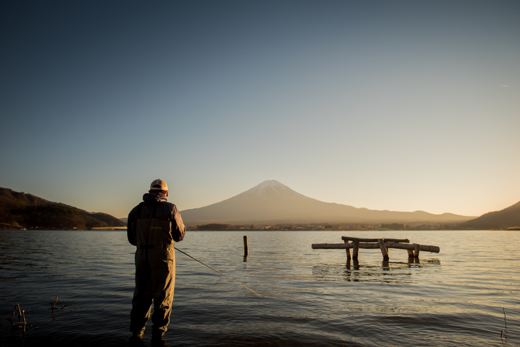 夕暮れ湖畔の釣り人