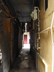 トタン屋根の路地裏の向こうの赤い階段