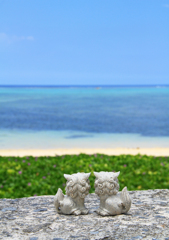 沖縄の青い海を見つめるシーサーカップル