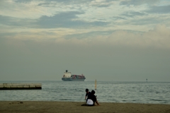 浜辺の親子とタンカー船